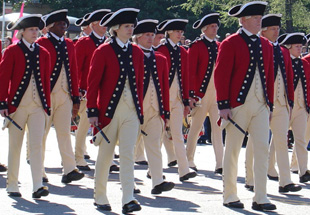 People dressed as colonial soldiers in a parade.