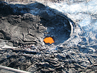 A large opening in the floor of pool 1 of the perched channel.  Below the crust is a large void and sluggish lava pond.  The pond occasionally overturns and hosts small bubble bursts.