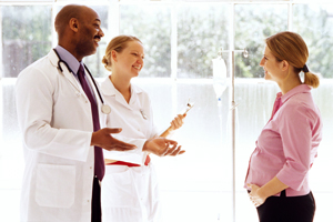 A picture of a pregnant woman talking to a doctor and a nurse