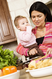 an infant and a mother in the kitchen preparing food