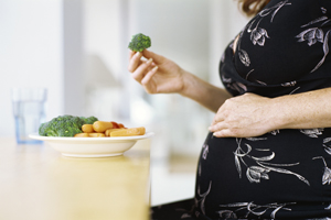A picture of a pregnant woman eating vegetables