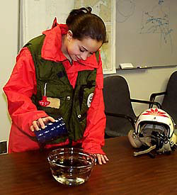 A student pours oil into a bowl of water.