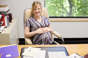A picture of a pregnant woman sitting at a desk