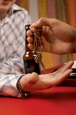 hand passing car keys to a alcohol drinking person