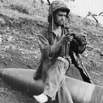 Soldier sitting on unexploded naval shell