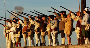Soldiers stand on the walls of the fort at sunset, muskets leveled at an unseen target. Grey smoke lingers in clumps surrounding them. Soldiers stand on the walls of the fort at sunset, muskets leveled at an unseen target. Grey smoke lingers in clumps surrounding them.