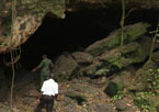 Two people standing at the python cave opening, home of the fruit bats thought to harbor Marburg virus.