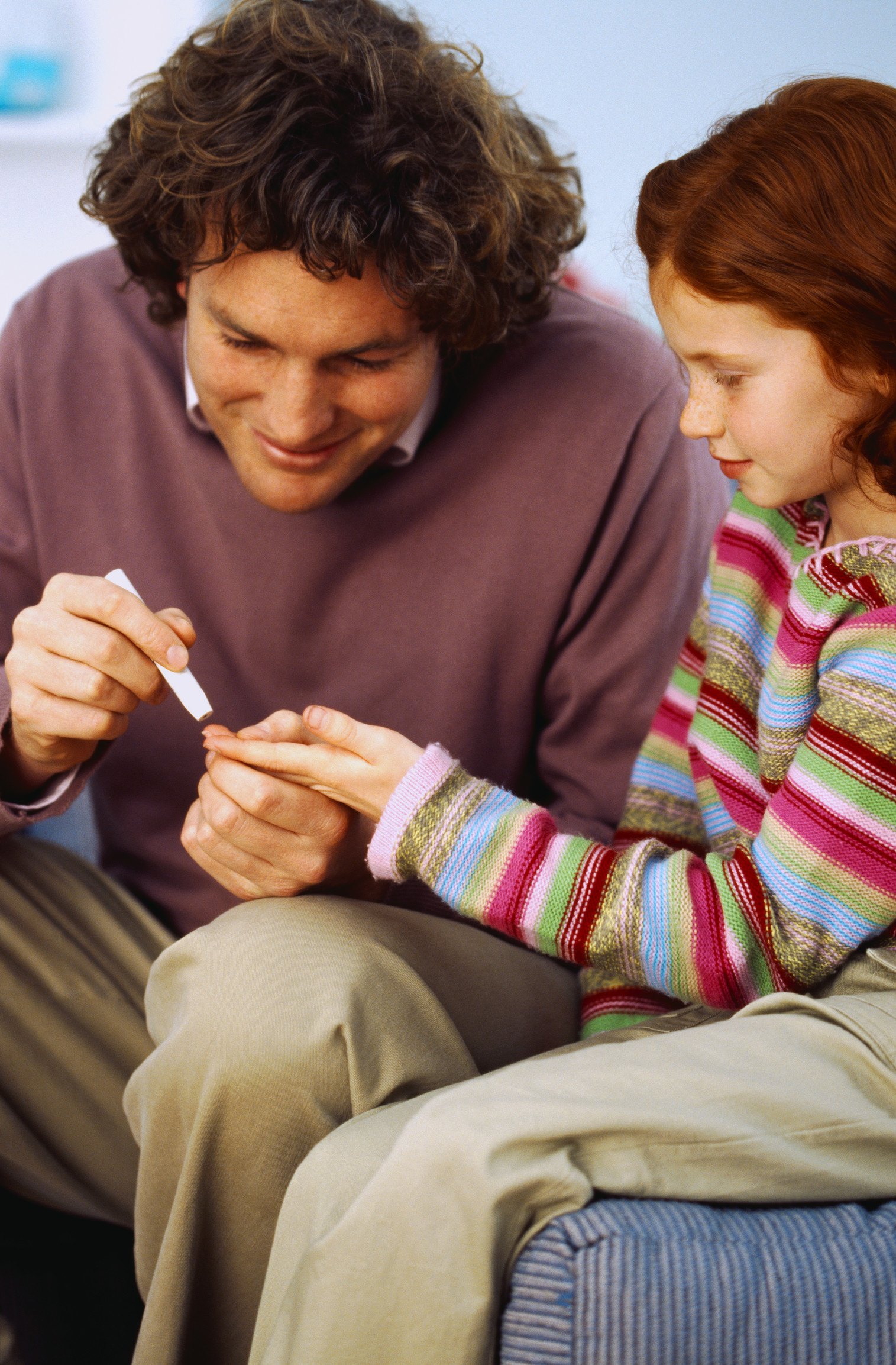 man giving diabetes test to young girl