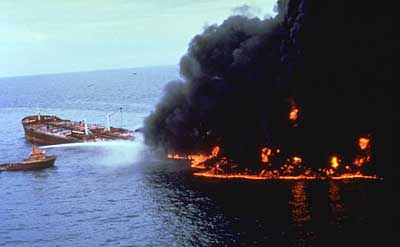 Ship partially on fire with smaller boat spraying water