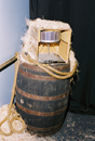 Model of an early TIROS satellite model inside a crate sitting on a wooden barrel