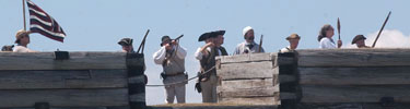 The fort wall is seen with a blue, white and red standard flutters, and soldiers in rank fires over the wall