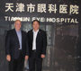 a photo of Dr. Sieving and Dr. Zhao standing in front of the Tianjin Eye Hospital.