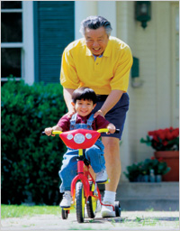 man helping son ride bicycle