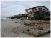 Photo of a house by a beach damaged by a hurricane.