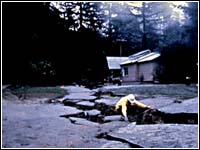 Photo of a man inspecting a huge crack in the ground left by an earthquake.