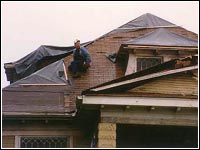 Photo of a person repairing his roof after a tornado.