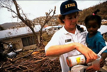 Photo of a FEMA employee giving a child juice.
