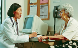 Female physician and older woman talking at a desk in an office setting