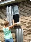 Ms. Sambuchino installing hurricane panels on her Biloxi home.