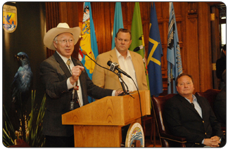 Secretary of the Interior Ken Salazar announces $280 million investment in U.S. Fish and Wildlife Service during a press conference at the Montana State Capitol in Helena. The secretary was joined by U.S. Senator Jon Tester (standing) and Montana Governor Brian Schweitzer (seated).  [Photo Credit: Tami A. Heilemann DOI]
