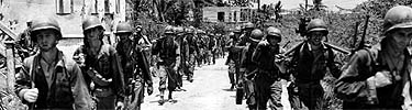 Marine infantrymen, close on the heels of the retreating Japanese, march through Agana, Guams' capital.