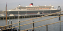 The Queen Mary 2, the largest ocean liner in the world, passing by the park with many smaller boats surrounding her.