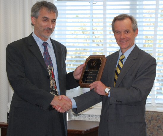   Assistant Secretary Cristopher Wall (right) presents a commemorative plaque noting the achievement to Julius Kozma of the Organisation for the Prohibition of Chemical Weapons.