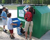 image of children dumping bins of paper into a mixed paper recycling collection bin.