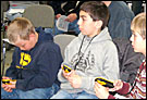 Three boys in an audience learning about geocaching.