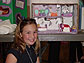 Young girl smiles at camera, science project in background.