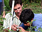 Man helps student aim digital camera at garden.