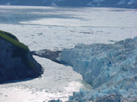 June 13, 2002, southwest-view from above the advancing terminus of Hubbard Glacier looking toward the push moraine that is blocking the mouth of Russell Fiord. A push moraine is sediment bulldozed from the floor of Russell Fiord by the advancing ice. Yakutat Bay is in the distance. The advancing terminus of the glacier is moving down Yakutat Bay and also into Russell Fiord.  This photograph was made at high tide. USGS Photograph by Bruce F. Molnia (6/13/02-46).