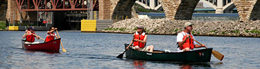 Canoeists boat past the historic Stone Arch Bridge.