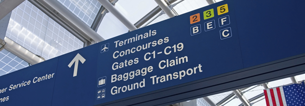 Large sign at airport with arrows showing the direction of certain terminals, concourses, gates, baggage claim, and ground transport