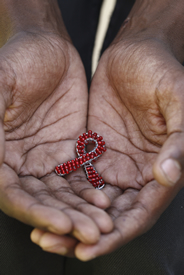An AIDS symbol hand made from red beads and wire, in the hands of an African man.