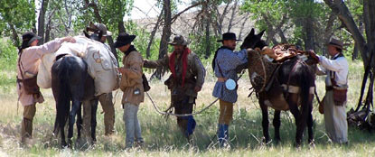 Men preparing mule for trip into the mountains.