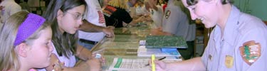 A park ranger reviews the junior naturalist worksheets for two children.