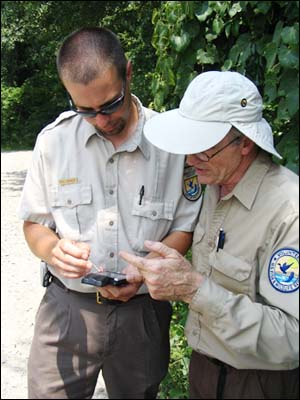 An FWS employee standing next to a volunteer using a handheld device to map invasive species.