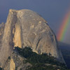 Photo of the mountain called Half Dome with a rainbow in the distance