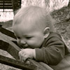 black and white photo of a baby, next to an old wheelbarrow
