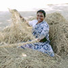 photo of a woman sitting in a pile of hay, twisting rope