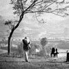 black and white photo of a valley with hills in the misty distance and a man pondering the beauty in the foreground