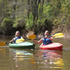 photo of two smiling kayakers near the river bank