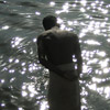 photo of a man standing in water, light sparkling on the waves