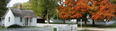 A small white cottage amid autumn foliage.