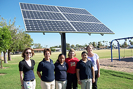 Group of school children standing in a field with solar panels