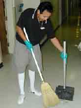 Worker sweeping with a broom into a dustpan