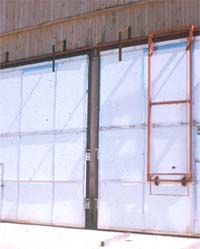 Mechanism at top of kiln doors to prevent toppling in case doors run off travel rails.