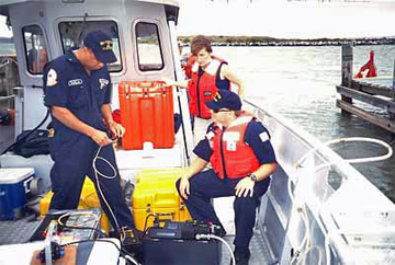 NOAA and Coast Guard workers prepare a fluorometer on a boat.