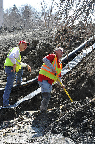 Flood engineers Chip Newman (r) and Steve Odegaard work to contain a leak in a levee along the Sheyenne River in Valley City, ND